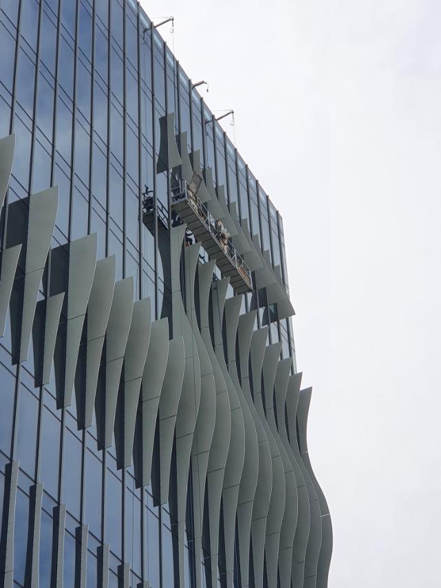 Damosa Diamond Tower in Davao, wavy facade fins being installed from a suspended platform